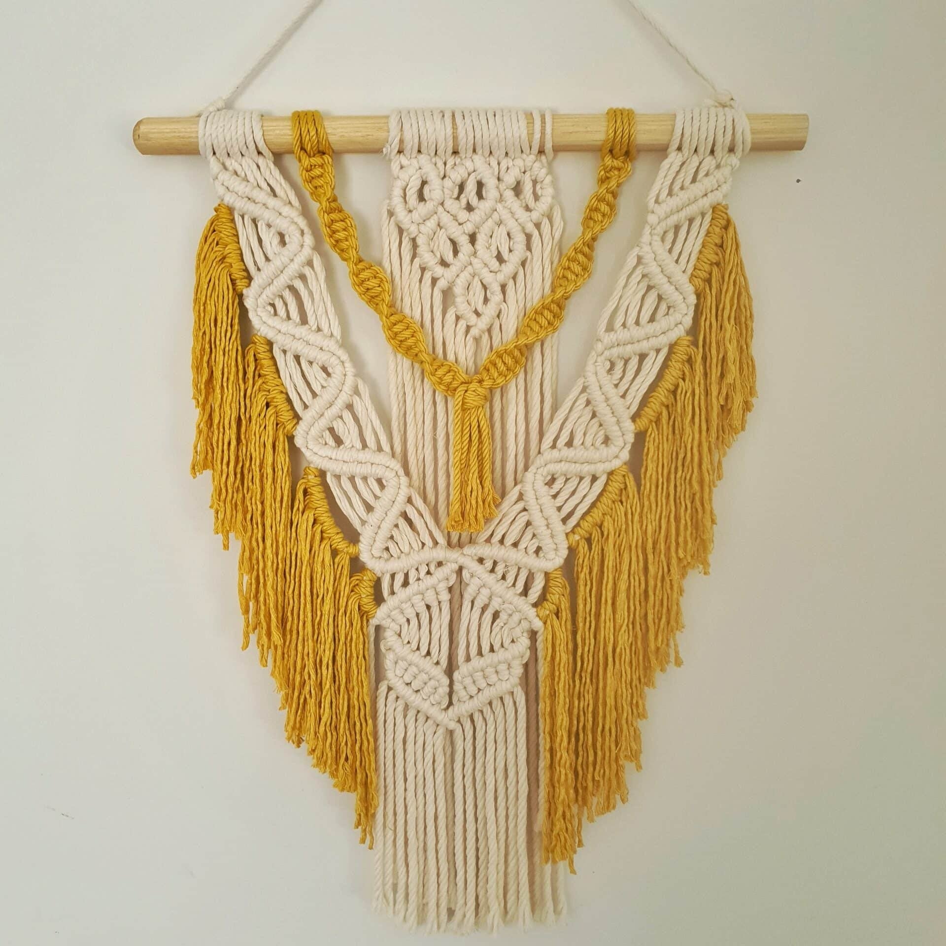 Décoration suspendue en macramé blanc cassé et jaune avec un support en bois