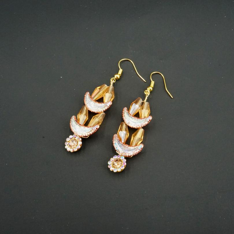Gold-colored earrings, shaped like crescent moons and golden flowers in pearls