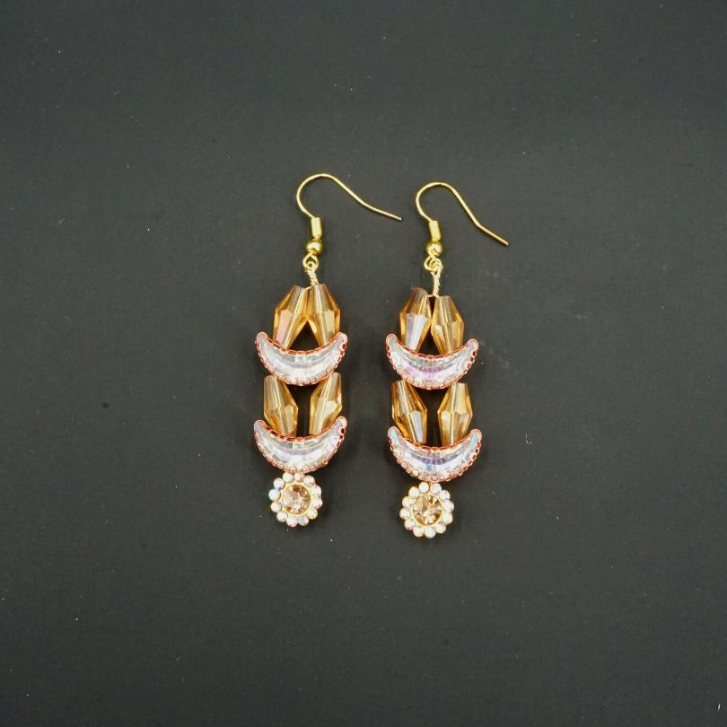 Gold-colored earrings, shaped like crescent moons and golden flowers in pearls