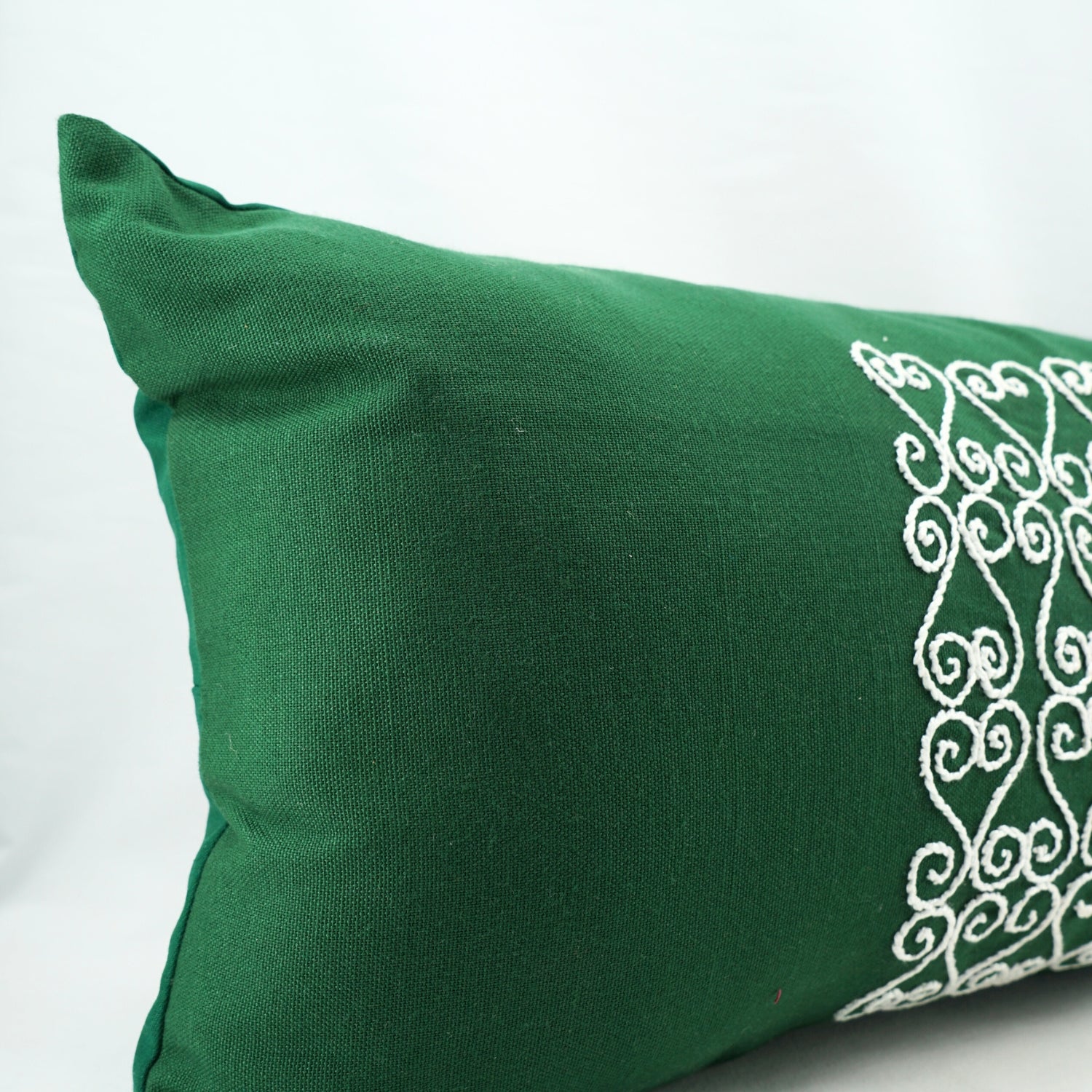 Coussin vert artisanal avec broderie blanche, élégance unique
