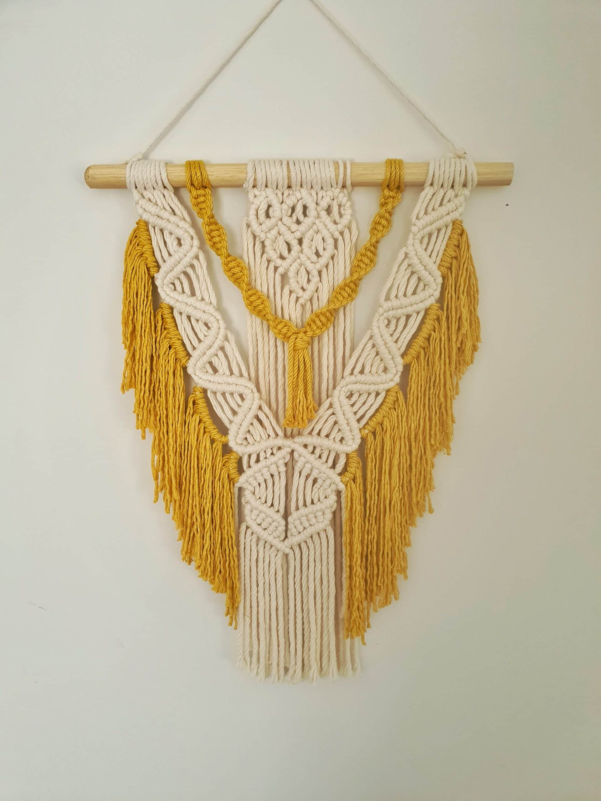 Décoration suspendue en macramé blanc cassé et jaune avec un support en bois