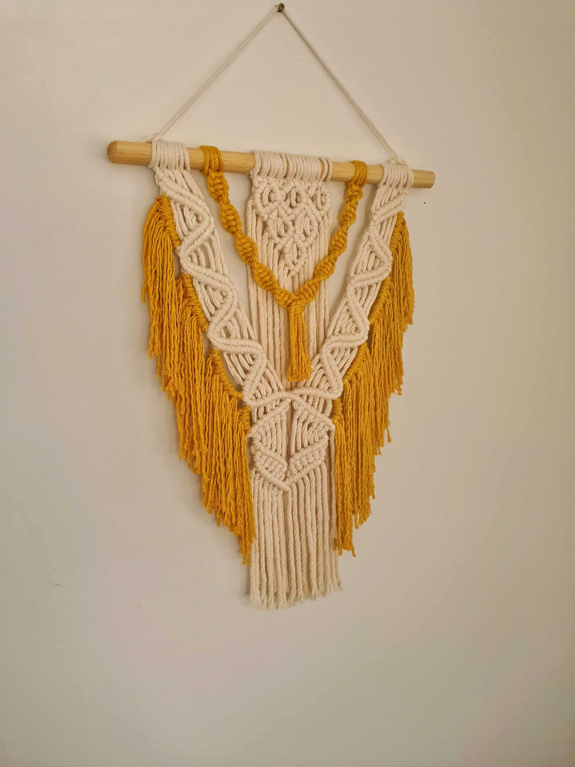 Décoration suspendue en macramé blanc cassé et jaune avec un support en bois