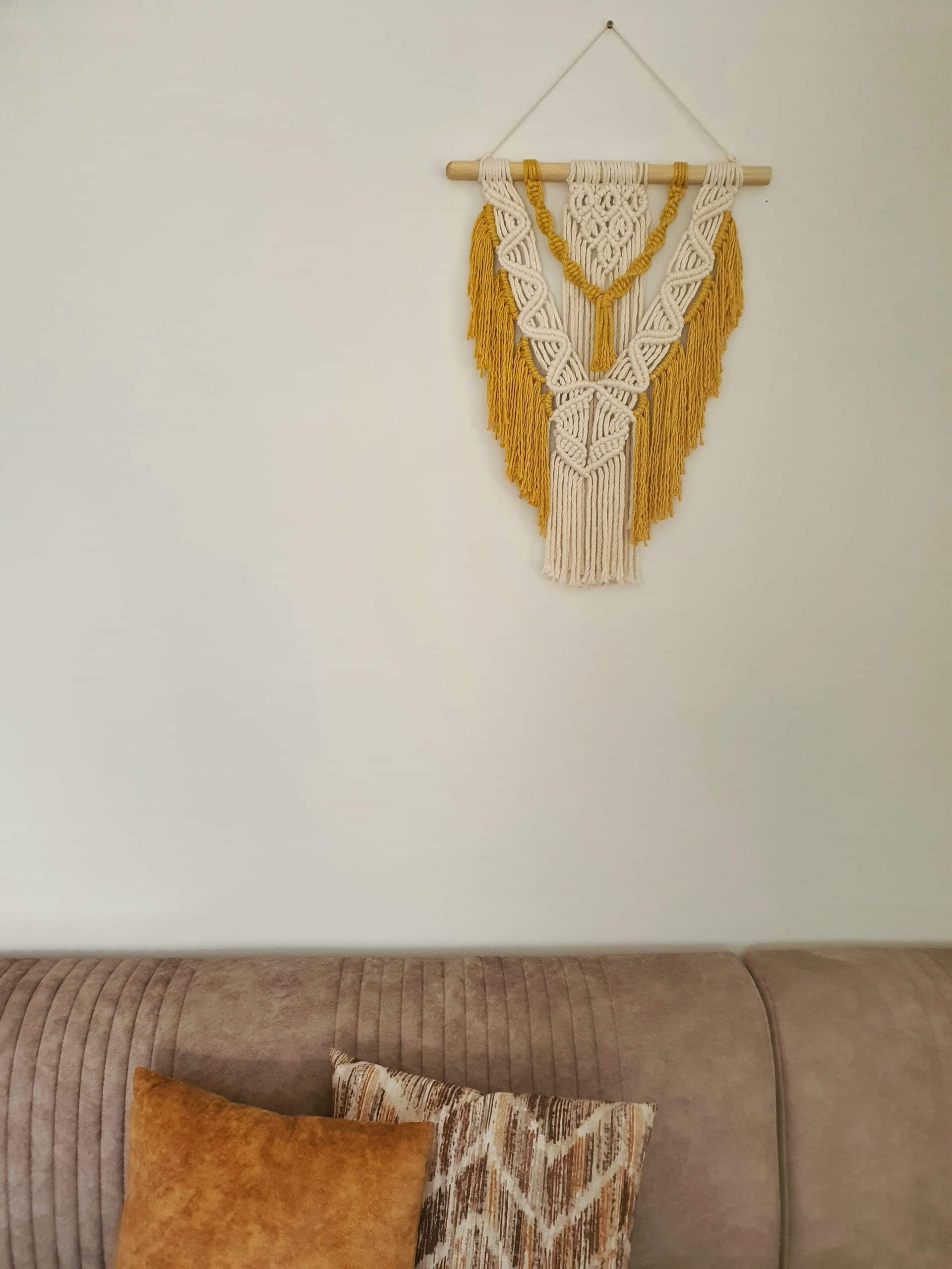 Décoration suspendue en macramé blanc cassé et jaune avec un support en bois