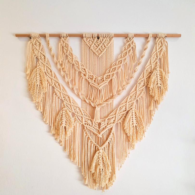 Off-white macrame hanging decoration with a wooden stand